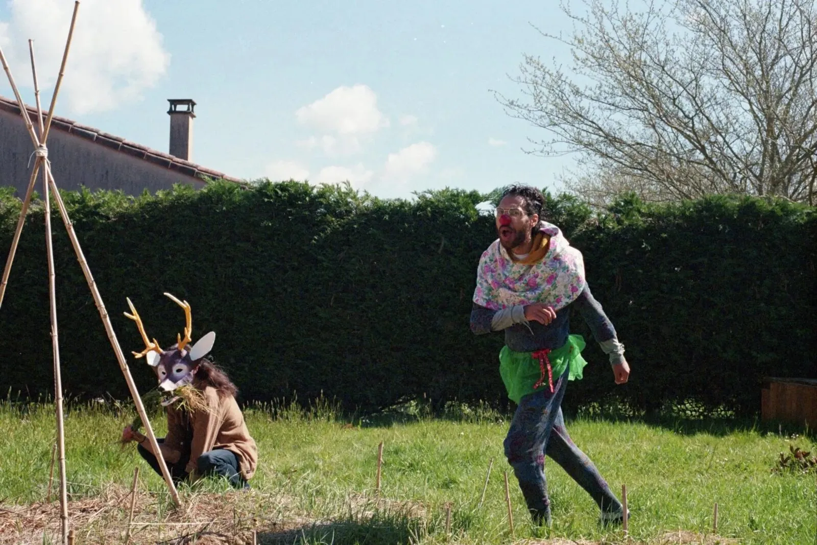 Deux personnes déguisées, l'une en cerf, l'autre en clown, courent dans un jardin